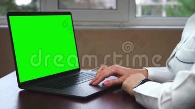 一位医生在一台带有绿色屏幕的笔记本电脑上工作的特写镜头。 科学家使用带有绿色屏幕色键的笔记本电脑